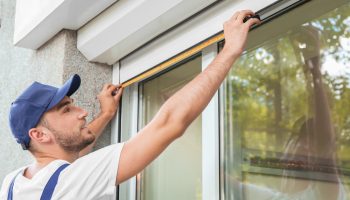 Man measuring window prior to installation of roller shutter outdoors