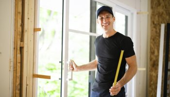 handsome young man installing Double Sliding Patio Door in a new house construction site