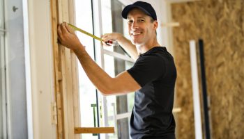 handsome young man installing Double Sliding Patio Door in a new house construction site